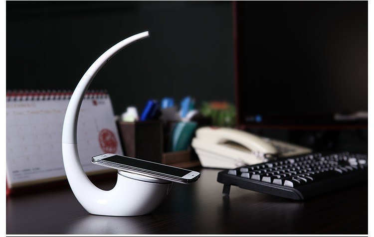 White phone stand with smartphone on a desk with office supplies in the background